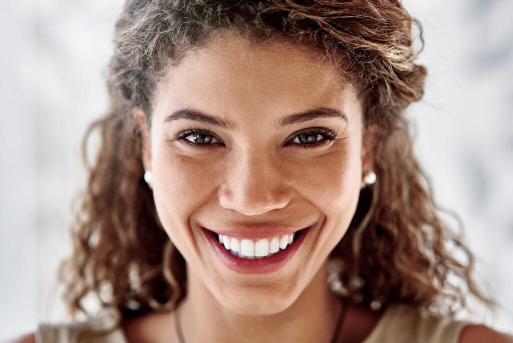 Femme souriante affichant une dentition éclatante après un traitement d’implantologie dentaire