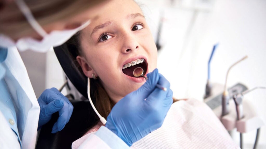 Examen dentaire d’une jeune patiente avec appareil orthodontique lors d’un contrôle de routine.