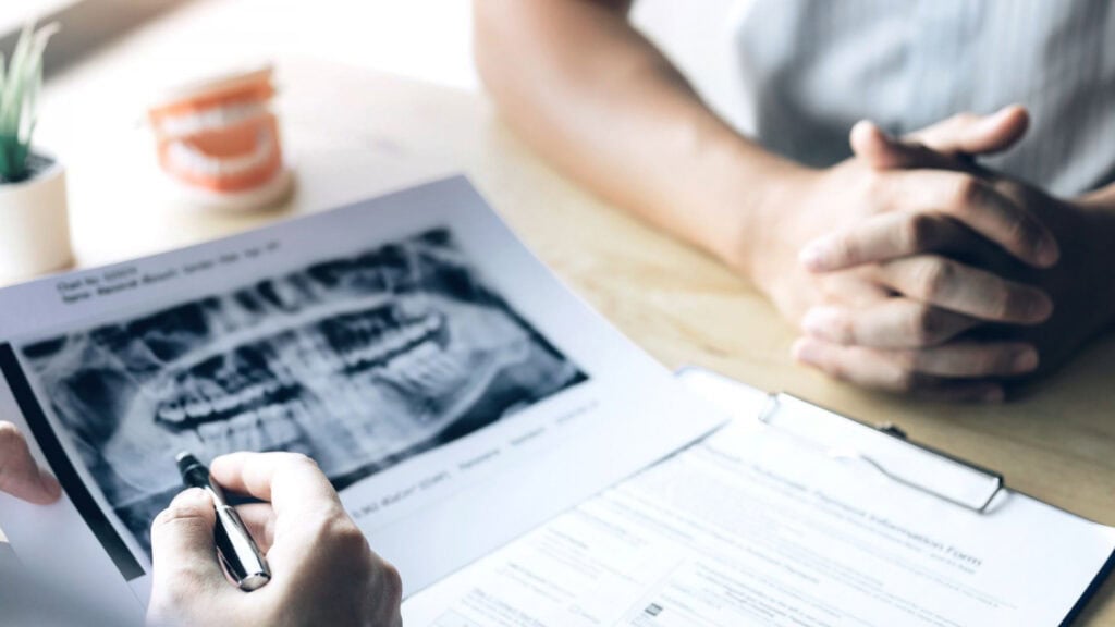 Consultation dentaire avec radiographie panoramique des dents présentée sur un document.