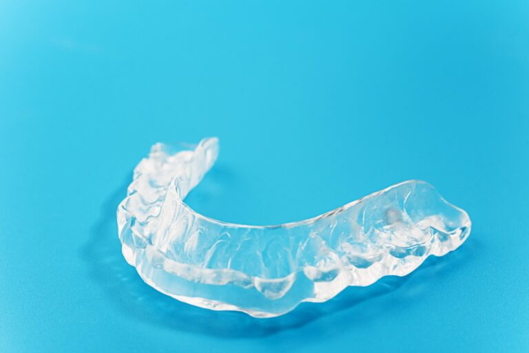 Gouttière dentaire ou protecteur buccal transparent sur fond bleu.